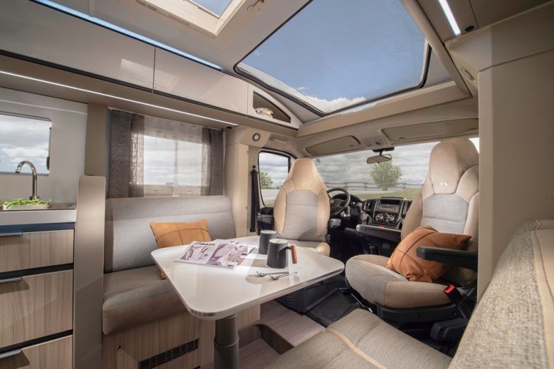 De leefruimte van de Adria Compact, met de dinette en de draaibare cabinezetels