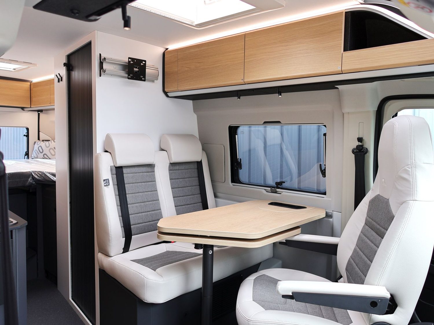 De leefruimte van de Adria Twin, met draaibare cabinezetels en de bedden achteraan