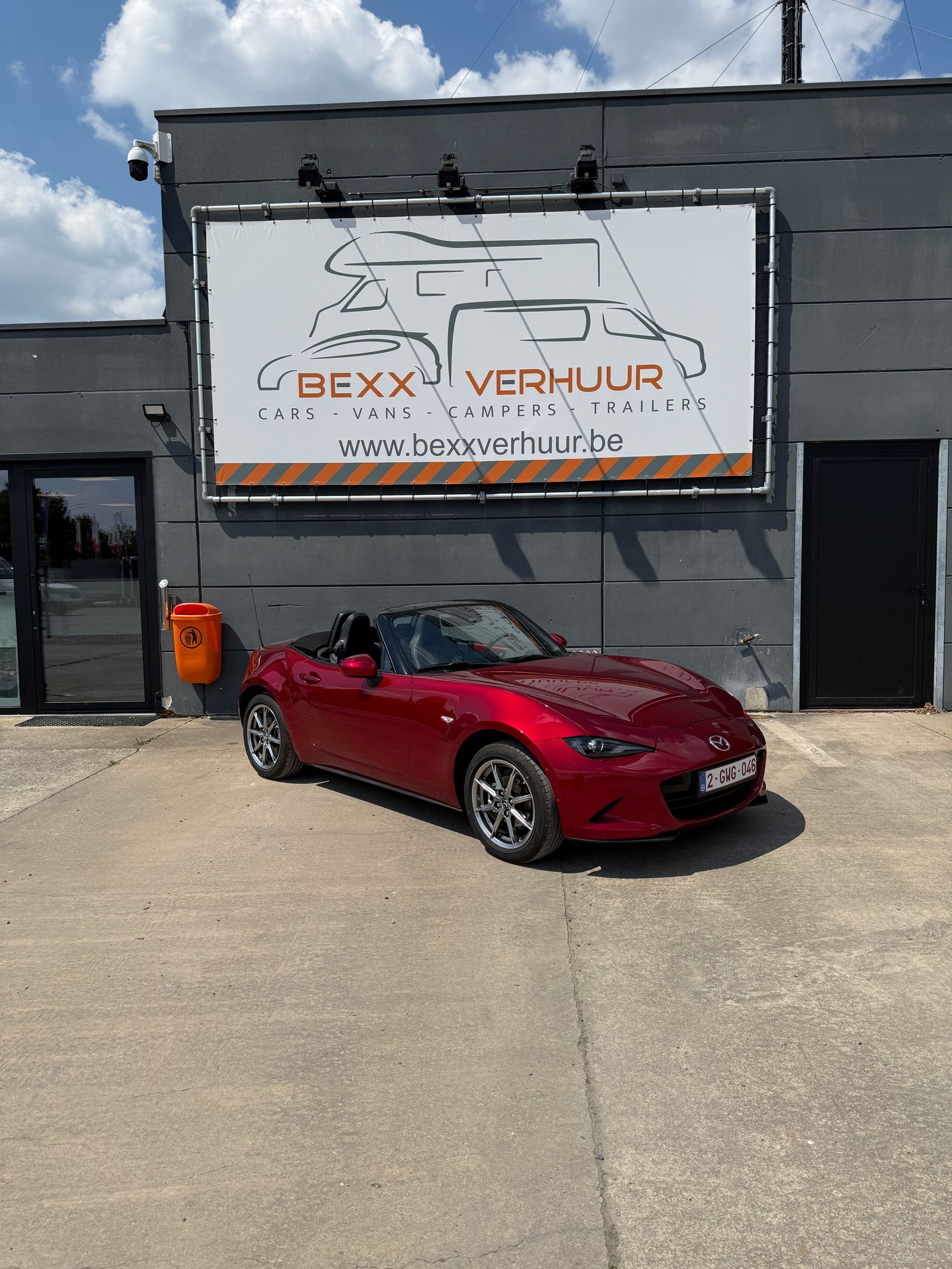 De rode MX-5 voor de loods, onder het uithangbord