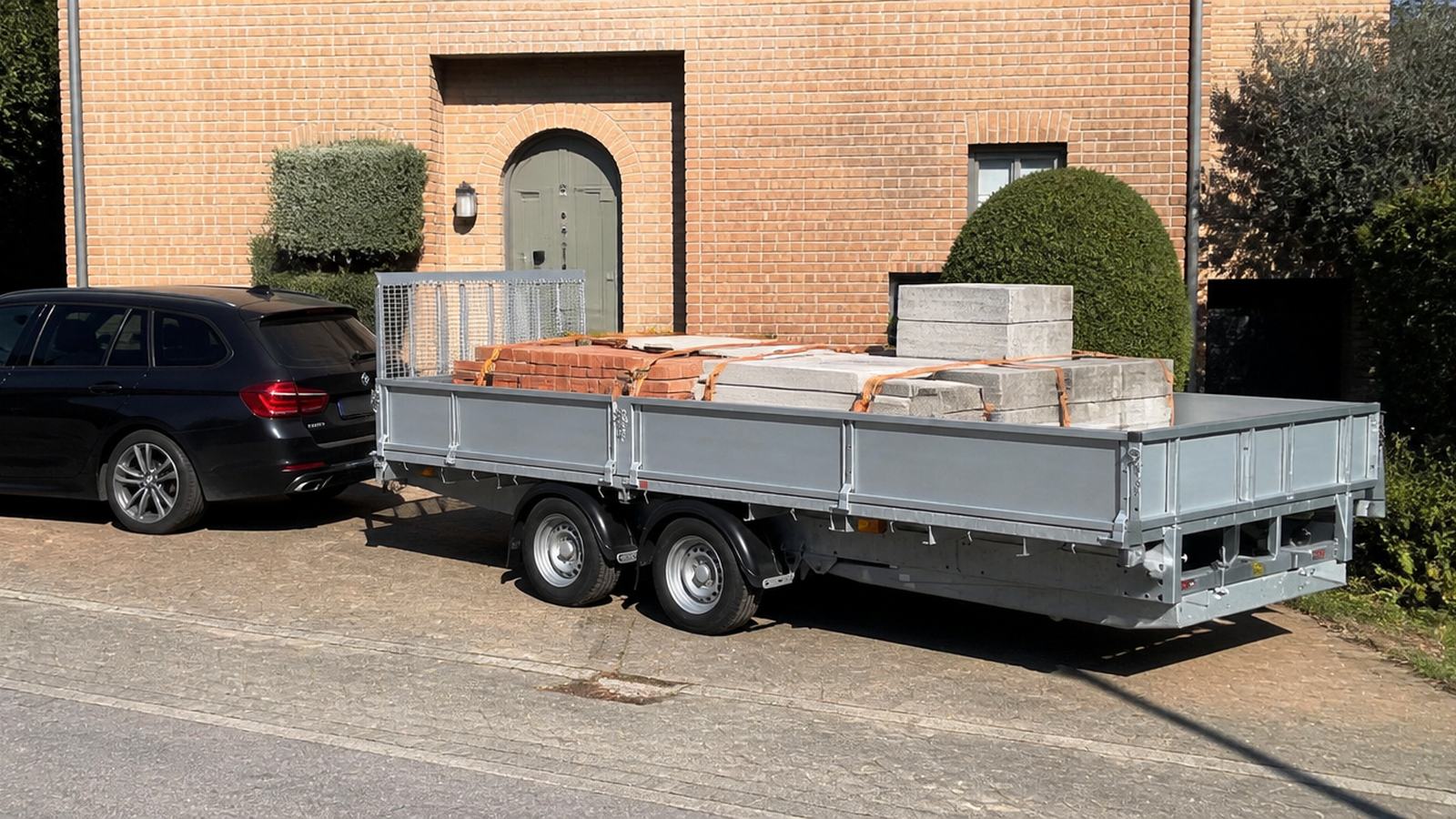 De multifunctionele trailer gekoppeld achter een wagen op een oprit (beeld van het model)