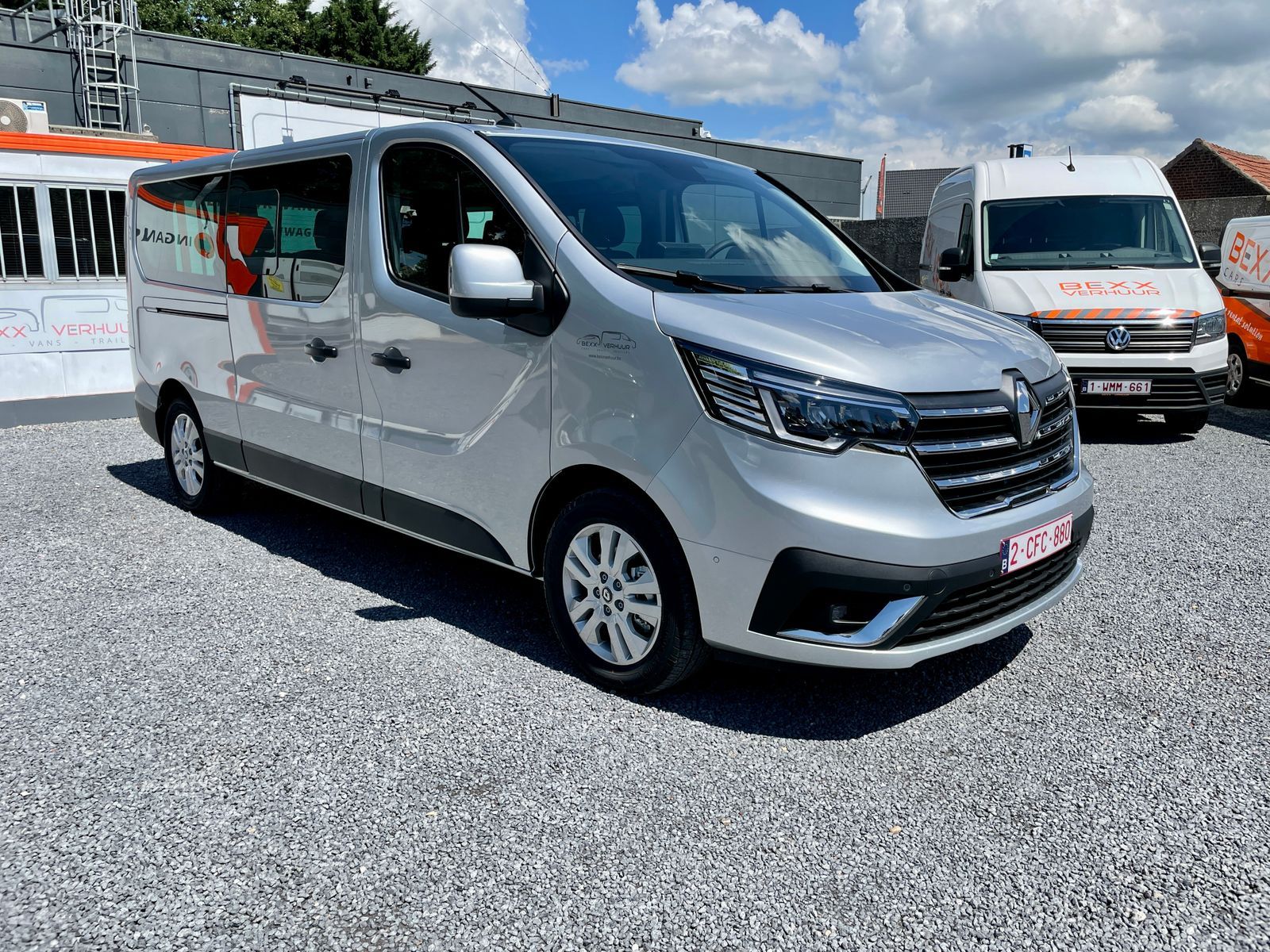 De zilvergrijze Trafic minibus op de kiezel bij de loods